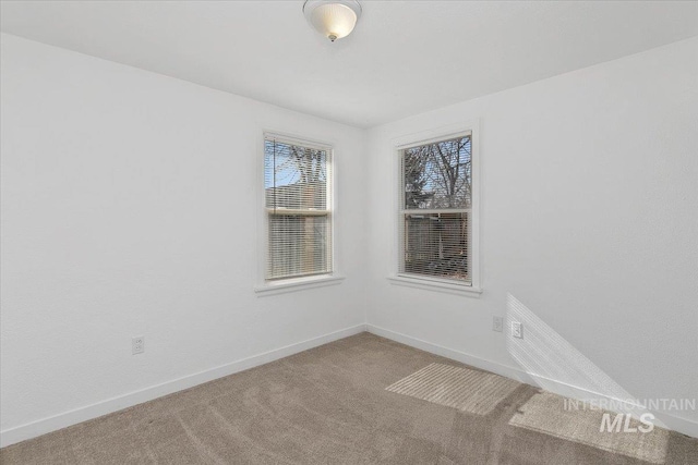 spare room featuring carpet floors and baseboards