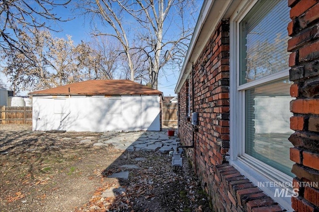 view of side of home featuring entry steps, stone siding, fence, and an outdoor structure