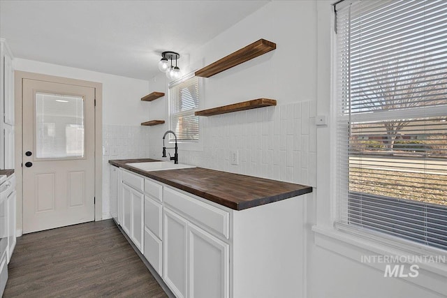 kitchen featuring butcher block counters, dark wood-style flooring, a sink, white cabinets, and open shelves