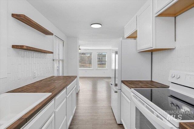 kitchen featuring butcher block counters, a sink, white cabinetry, open shelves, and white electric range oven