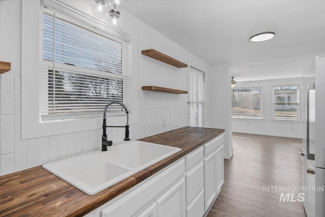 kitchen featuring white cabinets, ceiling fan, a sink, open shelves, and wooden counters