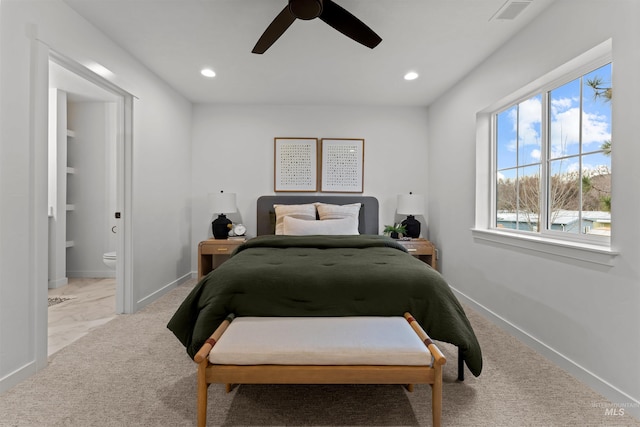 bedroom with ceiling fan, light carpet, and connected bathroom