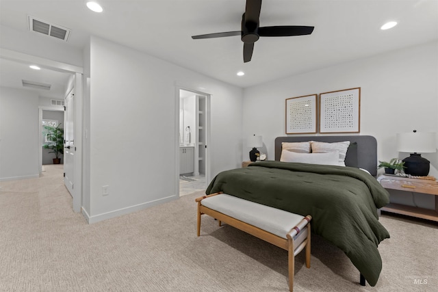 bedroom featuring light carpet, ensuite bathroom, and ceiling fan