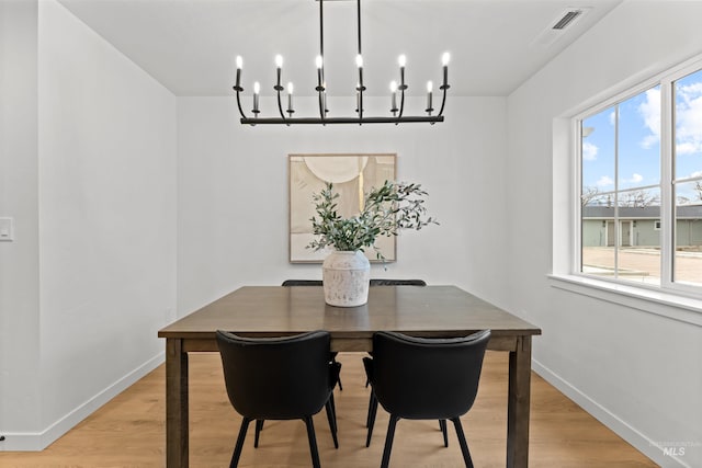 dining area featuring a healthy amount of sunlight, a chandelier, and light wood-type flooring