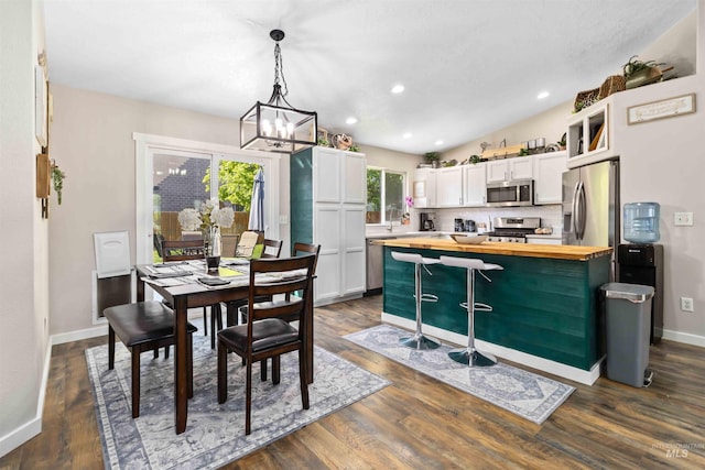 dining space featuring a chandelier, baseboards, dark wood finished floors, and recessed lighting