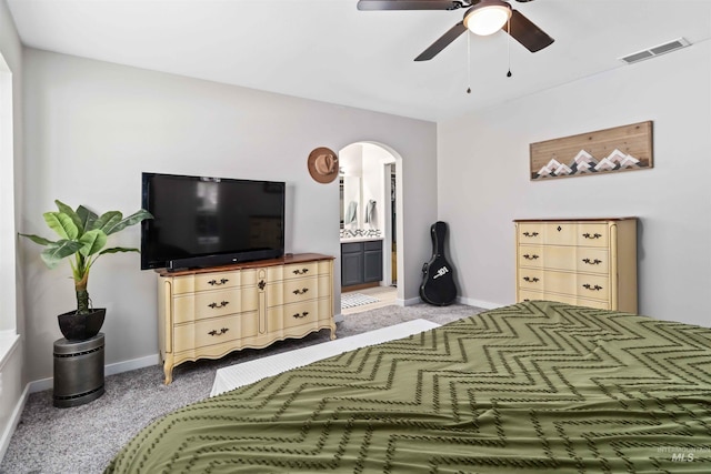 bedroom with carpet floors, arched walkways, baseboards, and ensuite bathroom