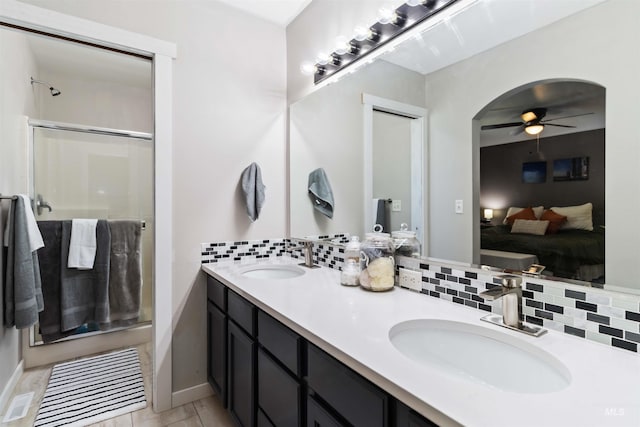 ensuite bathroom featuring a ceiling fan, a stall shower, decorative backsplash, and double vanity