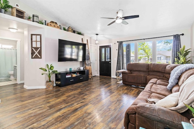 living area featuring baseboards, wood finished floors, ceiling fan, and vaulted ceiling