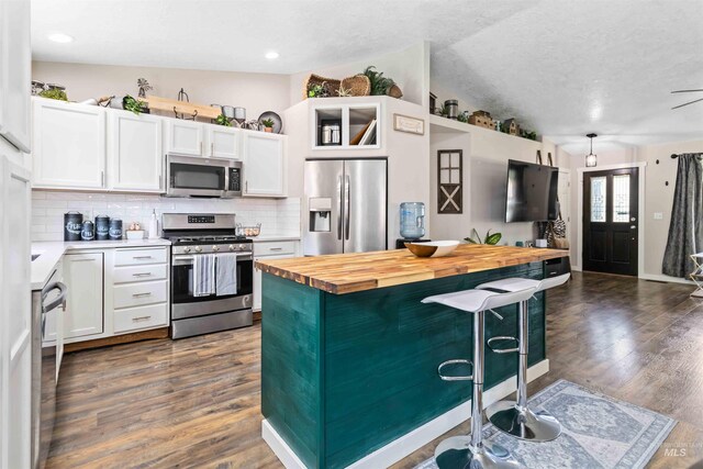 kitchen featuring appliances with stainless steel finishes, butcher block countertops, a breakfast bar, tasteful backsplash, and white cabinets