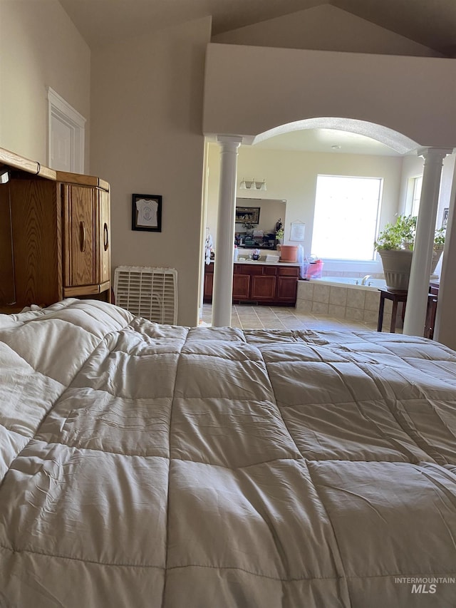 bedroom featuring vaulted ceiling and decorative columns