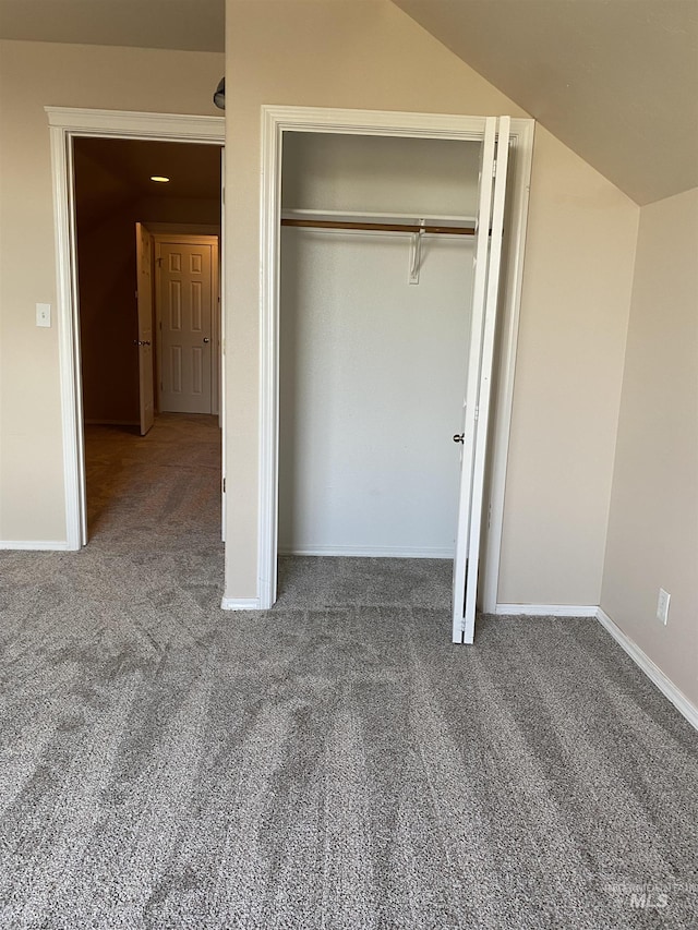 unfurnished bedroom featuring vaulted ceiling, carpet, and a closet