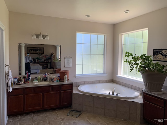 bathroom featuring a relaxing tiled tub, vanity, and tile patterned floors