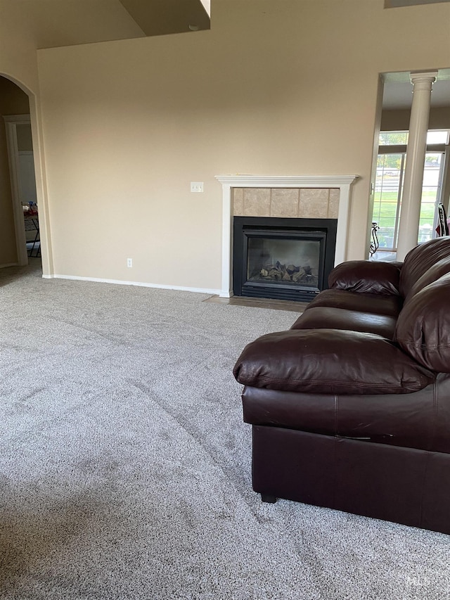 carpeted living room with a fireplace and ornate columns