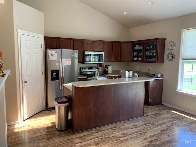 kitchen with dark brown cabinetry, high vaulted ceiling, stainless steel appliances, and light hardwood / wood-style floors