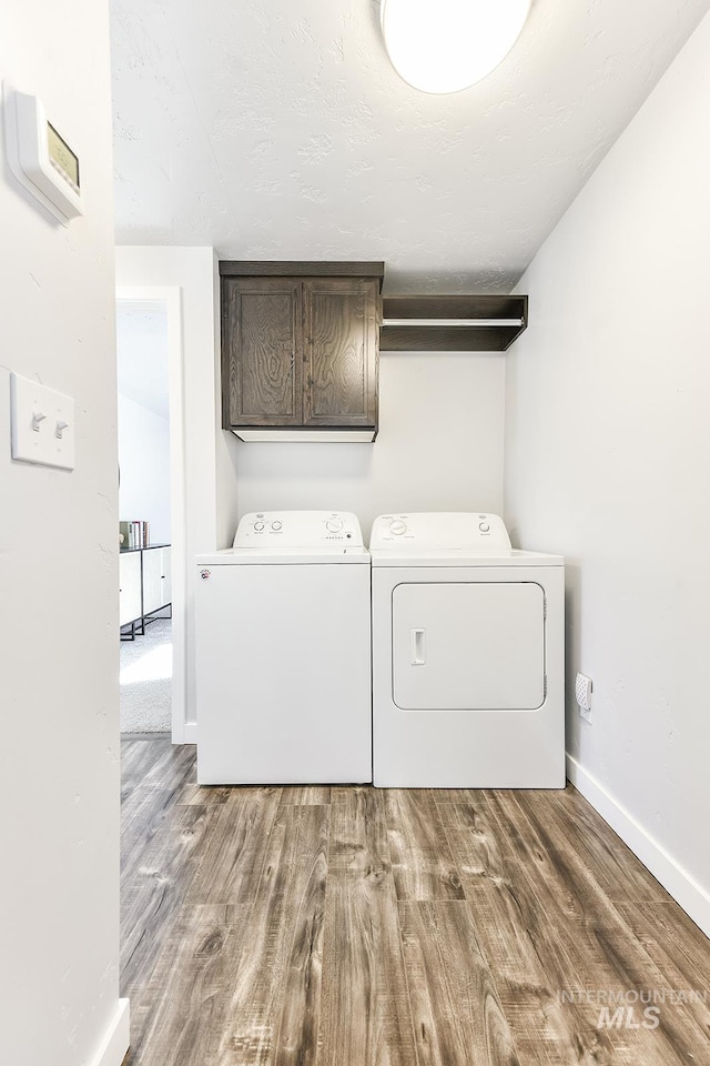 washroom with independent washer and dryer, cabinets, and hardwood / wood-style floors