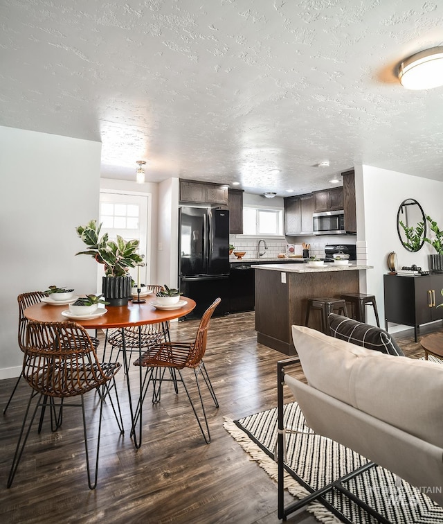 dining space with sink, dark hardwood / wood-style floors, and a textured ceiling