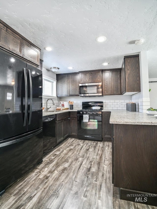 kitchen with tasteful backsplash, light wood-type flooring, dark brown cabinetry, and black appliances