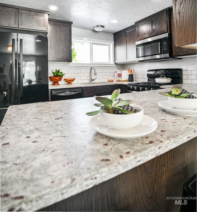 kitchen with tasteful backsplash, sink, black appliances, dark brown cabinets, and a textured ceiling