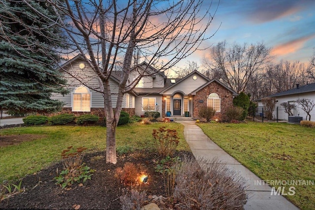 view of front facade featuring a front yard, fence, and brick siding