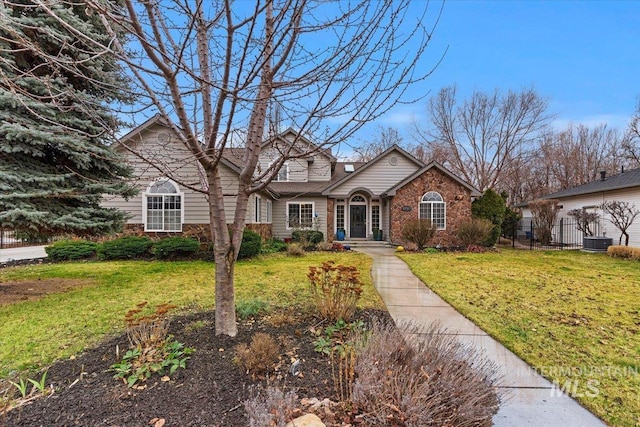 traditional-style home featuring brick siding, a front lawn, and fence