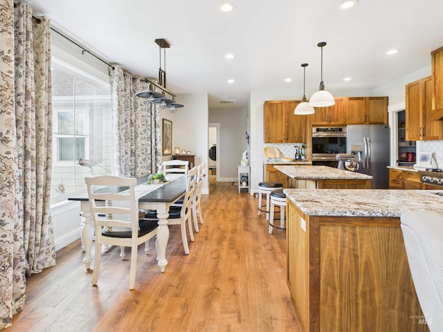 515 School St, Albion, ID 83311 - kitchen with appliances with stainless steel finishes, a center island, brown cabinetry, decorative backsplash, and recessed lighting