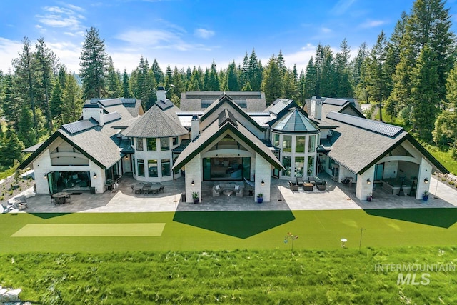 back of property featuring a patio, an outdoor hangout area, and a lawn