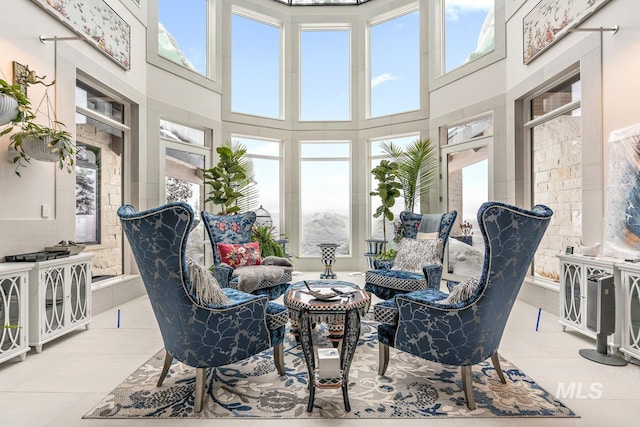 living room featuring plenty of natural light, a high ceiling, and light tile floors