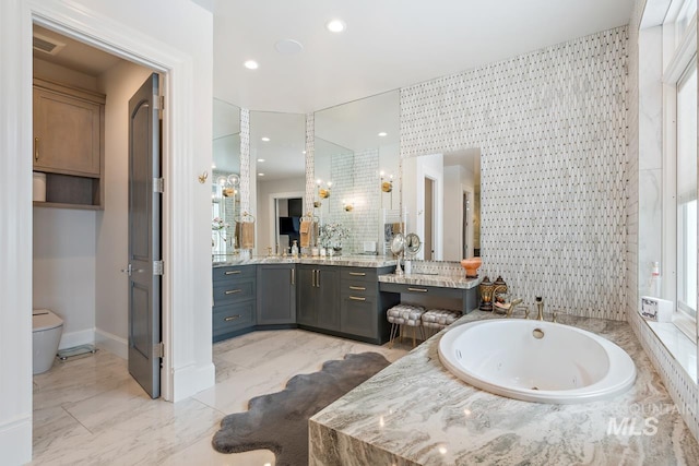 bathroom featuring tiled tub, toilet, tile floors, and vanity