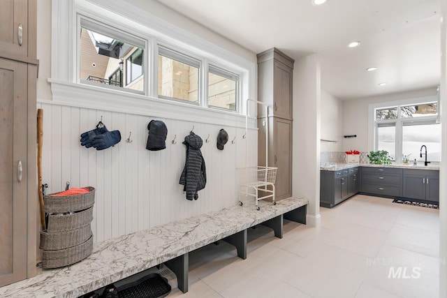 mudroom with a skylight, sink, and light tile floors