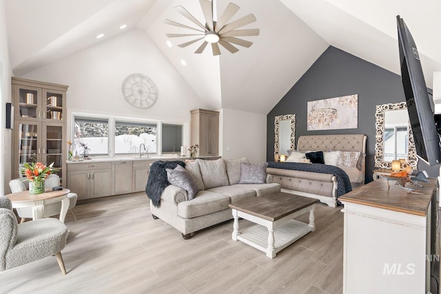 living room featuring high vaulted ceiling, light hardwood / wood-style floors, and sink