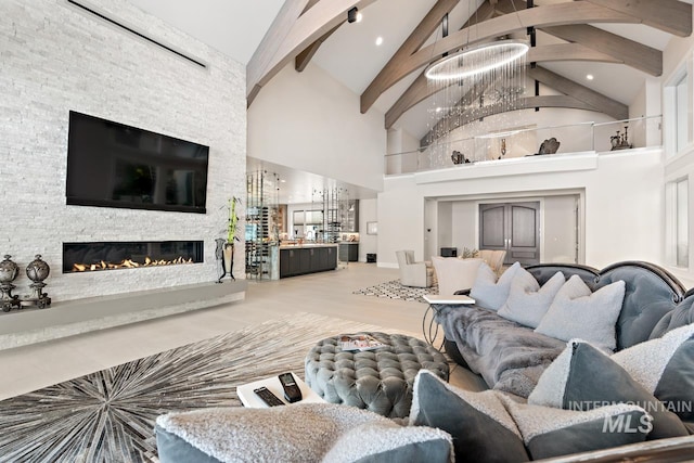 living room featuring high vaulted ceiling, a fireplace, beam ceiling, a notable chandelier, and hardwood / wood-style flooring