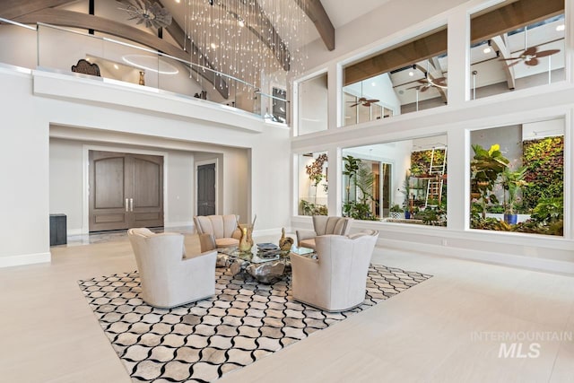 living room with beamed ceiling, ceiling fan, and a towering ceiling