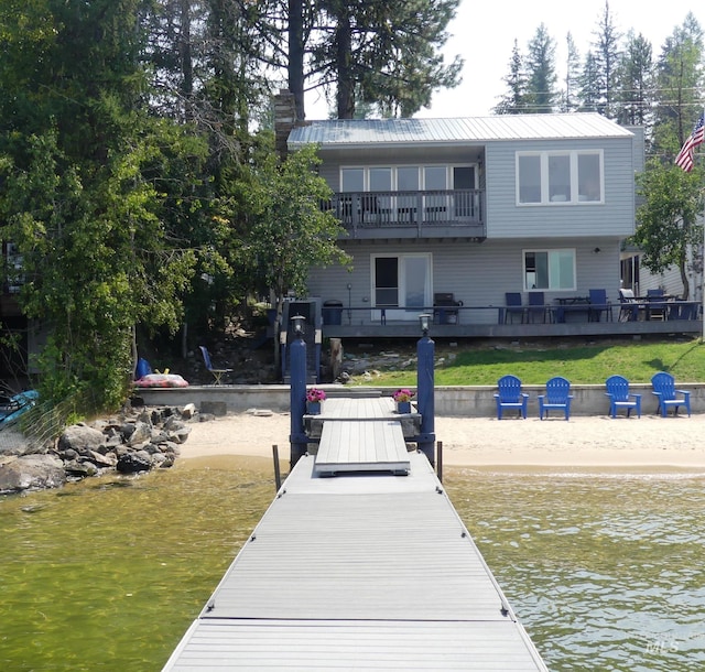 view of dock with a deck with water view and a balcony