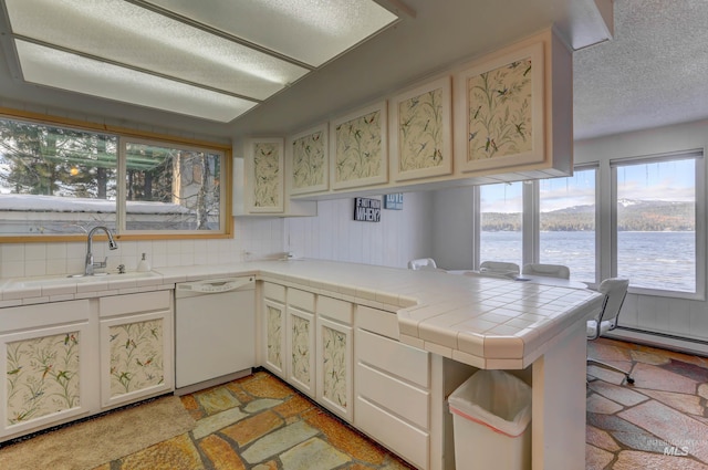 kitchen featuring white dishwasher, tile countertops, sink, a water view, and kitchen peninsula