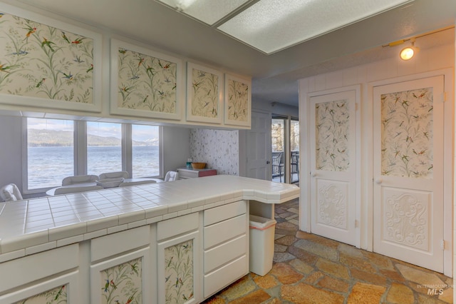 kitchen featuring light tile patterned floors, a wealth of natural light, a water view, and tile countertops