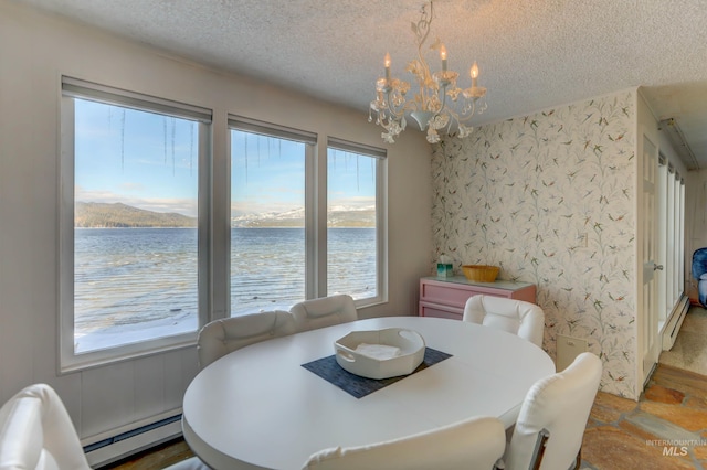 dining space with a textured ceiling, a baseboard radiator, plenty of natural light, a water view, and a notable chandelier