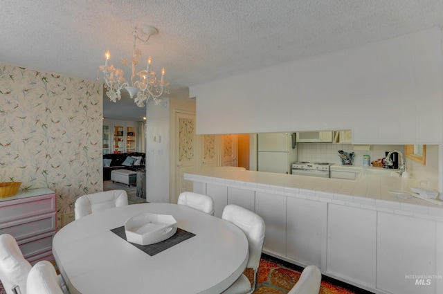 dining room featuring sink, a chandelier, and a textured ceiling