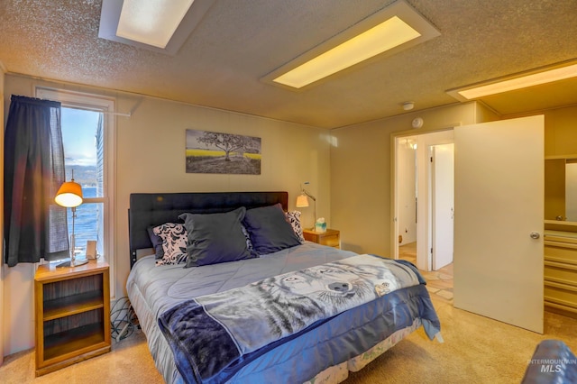 bedroom featuring a textured ceiling, light colored carpet, and multiple windows