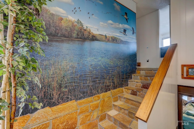 staircase with a water view and tile patterned flooring