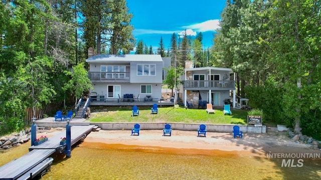 rear view of house featuring a lawn, a deck, and a balcony