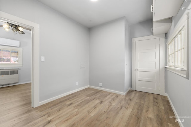 710 N 15th St, Boise, ID 83702 - unfurnished room with radiator heating unit, an AC wall unit, light wood-type flooring, and ceiling fan