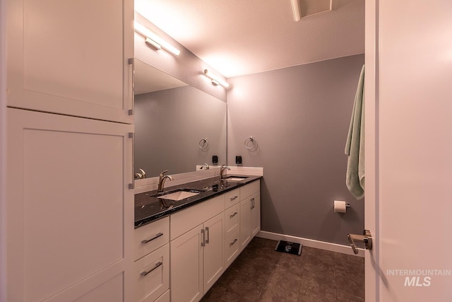 bathroom with double vanity, a sink, visible vents, and baseboards