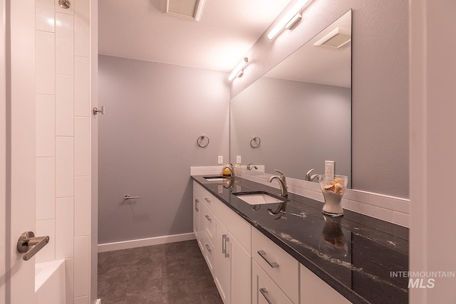 full bathroom featuring visible vents, a sink, baseboards, and double vanity