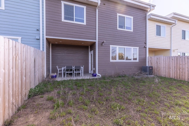 back of house featuring a fenced backyard, central AC, and a patio