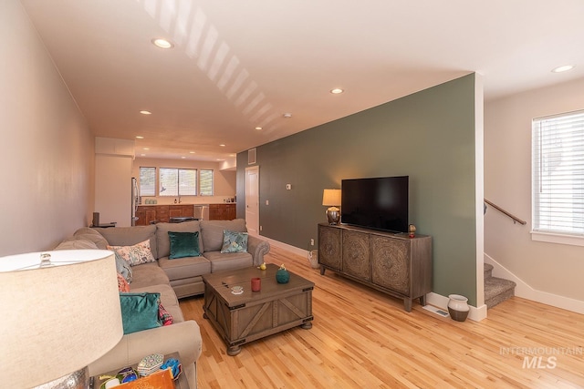 living room featuring stairs, baseboards, light wood-style flooring, and recessed lighting