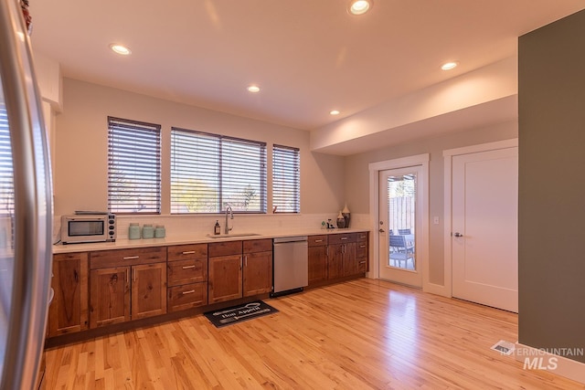 kitchen with stainless steel appliances, a healthy amount of sunlight, light countertops, and a sink