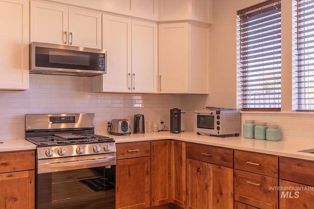 kitchen with stainless steel appliances, white cabinets, and light countertops