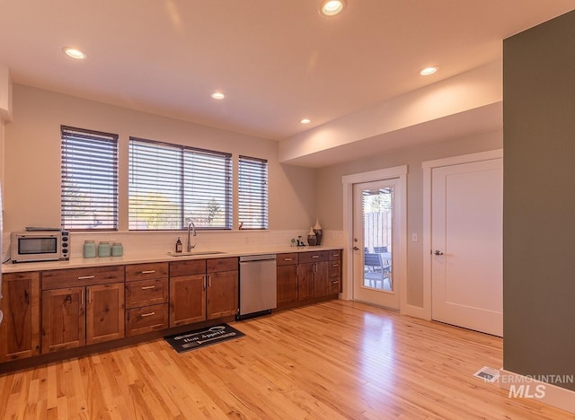 kitchen featuring stainless steel appliances, light countertops, a sink, and light wood-style flooring