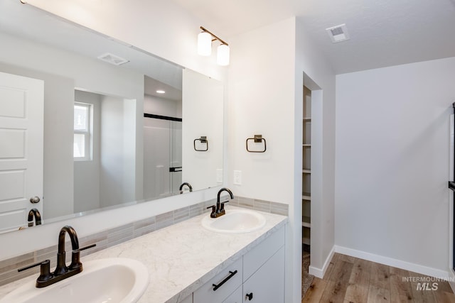 bathroom featuring vanity, hardwood / wood-style floors, backsplash, and a shower with shower door