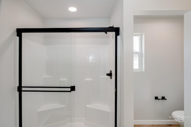 bathroom with a shower with shower door and toilet